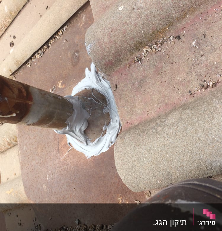 צינור מתכת עם איטום לבן על גג רעפים